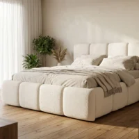 تخت خواب لمباردی با بدنه پارچه‌ای سفید و روتختی طوسی، در اتاقی با نور طبیعی و گیاهان سبز کنار پنجره