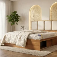 تخت خواب سلین در نمای سه‌رخ داخل اتاق روشن؛ هدبورد پارچه‌ای چهار تکه با انحنای نیم‌دایره‌ای در دو طرف، قاب چوبی گرم و تخت با روتختی کرم و پتو روی لبه تخت دیده می‌شود