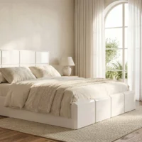 تخت خواب ورونیا با طراحی مدرن و رنگ سفید، در اتاق خوابی با پنجره بزرگ و پردههای حریر، همراه با روتختی کرم و بالشهای طرحدار